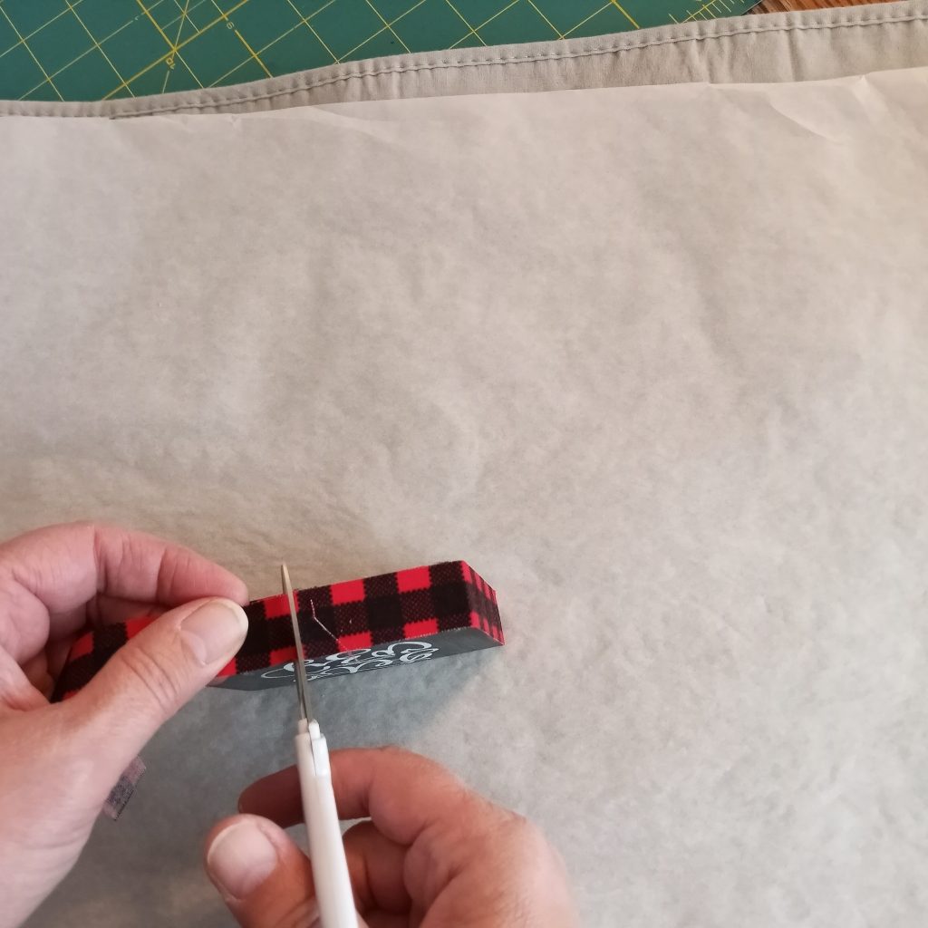 Cutting the end of the fabric fused with Wonder-Under® after applying to wood #tieredtraydecor
