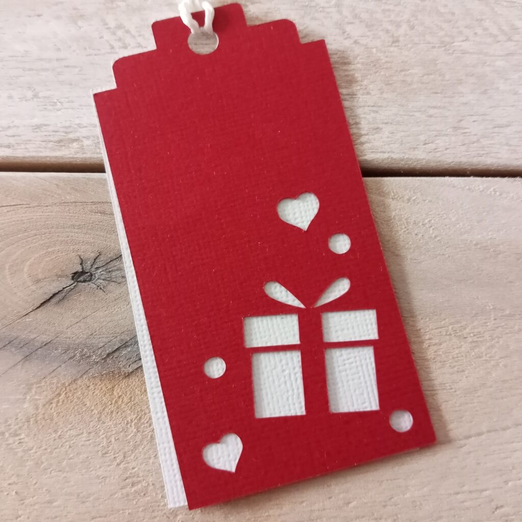Layered Christmas Tag: Two layers of a beautifully crafted tags, one white with hidden names, the other cut from colored textured cardstock. 