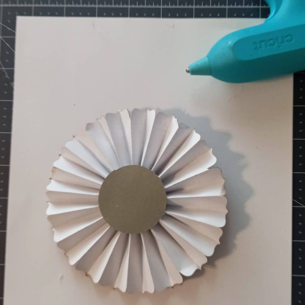 Use a glue gun to add a cardstock circle to a paper rosette